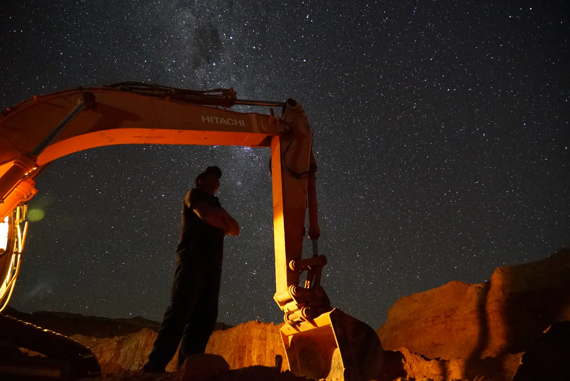 Dan Measey standing beneath an excavator under the Coober Pedy night sky